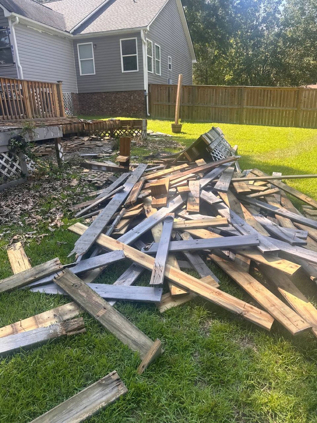 Pile of old deck boards in a backyard before removal